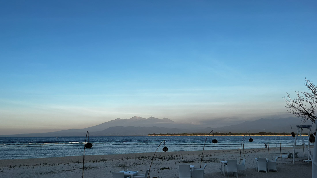 Stühle für Dinner am Strand mit Lombok im Hintergrund