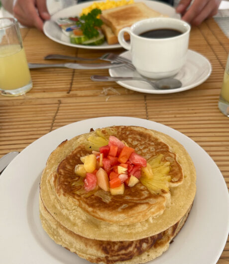 Pancakes mit Obst und Kaffee am Frühstückstisch