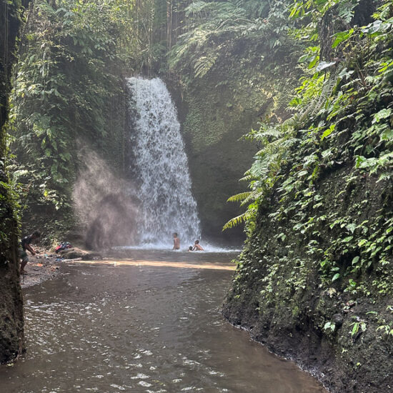 Bali Wasserfall mit Wasserbecken davor im Dschungel und spielende Kinder